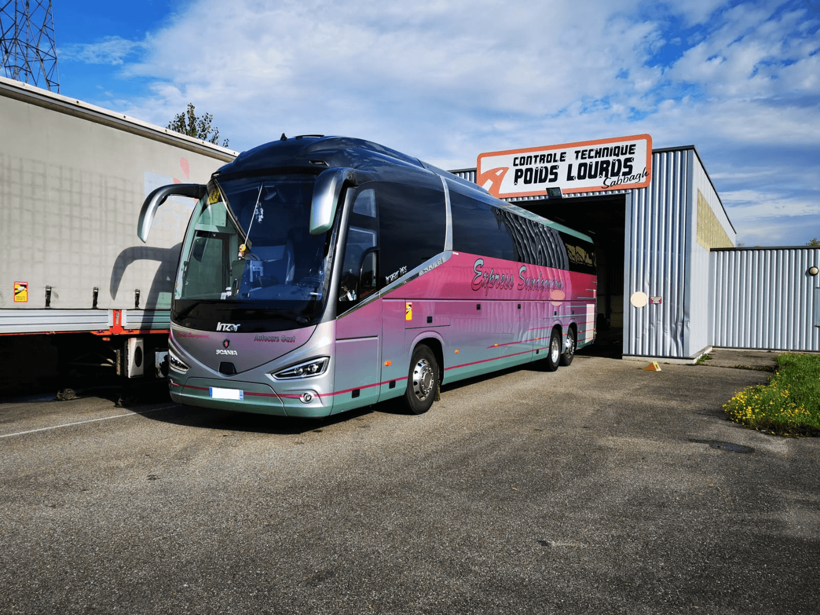 Autocar de tourisme rose et gris entrant au centre poids lourds